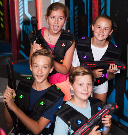 Group portrait of happy teenagers with laser guns having fun on dark lasertag arenaの写真素材
