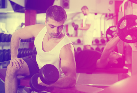 Portrait of athletic man exercising with dumbbells in gymの写真素材