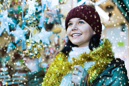 Smiling satisfied friendly  teenage girl shopping at festive fair before Xmasの写真素材