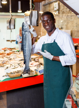 Confident male shop assistant selling fresh fish and chilled seafood