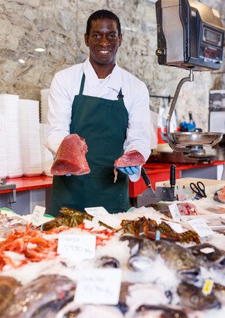Confident male shop assistant selling fresh fish and chilled seafoodの写真素材