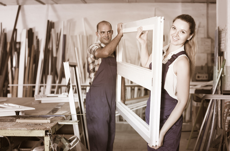 Two positive professional workers working in assembly shop of plastic windowsの写真素材