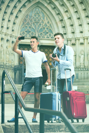 male couple sightseeing and taking pictures on camera and smartphone on the street of the cityの写真素材