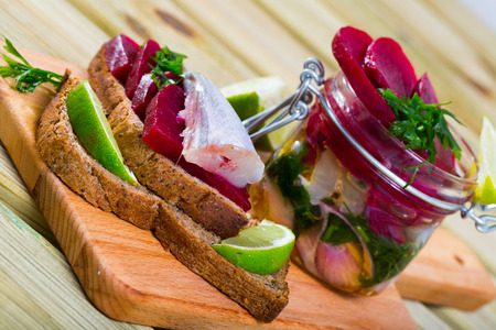 Pickled whiting in homemade marinade of olive oil and lime juice with beets, onion and greens served with rye breadの写真素材