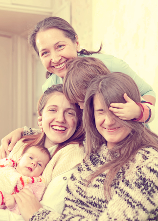 Happy grandmother with her daughters and granddaughters in homeの写真素材