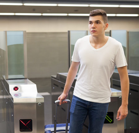 Young male passenger in casual clothing near baffle gate  in underground platform