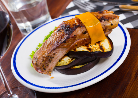 Delicious pork rib baked with cheese slice served with grilled eggplant, fresh lettuce and onionの写真素材