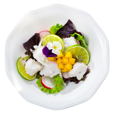 Top view of piquant cod ceviche with lime slices, chopped mango, lettuce and radish. Isolated over white backgroundの写真素材