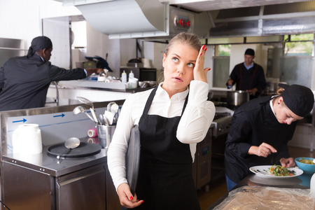 Young waitress expressing dissatisfaction and disappointment with not cooked ordered meals in restaurant kitchenの写真素材