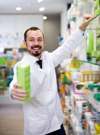 Glad pharmacist suggesting useful drug in pharmacyの写真素材