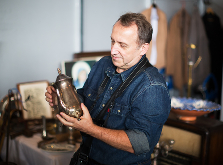 Mature man with camera consider things in flea marketの写真素材