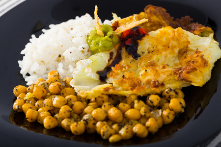 Plate with leaves in batter with garbanzos, rice and different saucesの写真素材