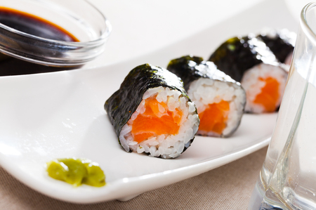 Sushi menu. Maki rolls with salmon served with wasabi and soy sauce on white plateの写真素材