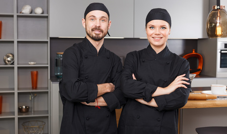 Portrait of two confident personal chefs standing in modern interior of private kitchenの写真素材