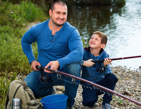 Portrait of  father and cute son fishing with rods in summer dayの写真素材