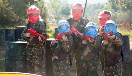 Portrait of team of boys and girls paintball players with marker guns ready for game outdoorsの写真素材