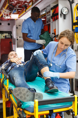 Ambulance team providing medical care to patient on stretcher in ambulance carの写真素材