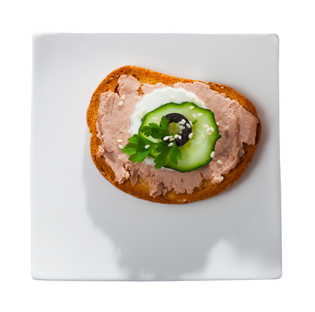 Top view of toast with meat pate, fresh cheese and vegetables served on white plate. Isolated over white backgroundの写真素材