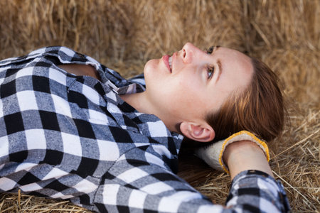 Portrait of positive woman farmer lying on strawstack resting during work