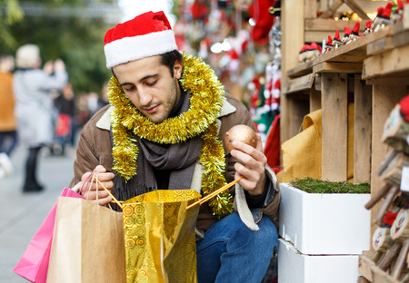 Smiling man in hat choosing decorations at Christmas market outsideの写真素材
