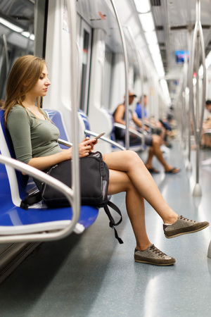 Woman is sitting in train and looking in the phone in the underground.の写真素材