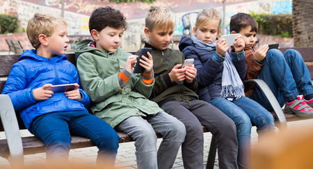 Children playing on smartphone outdoorsの写真素材