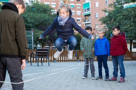Happy kids skipping on chinese jump rope on playground in autumn dayの写真素材