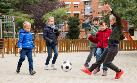 Company of kids are jogning and playing football