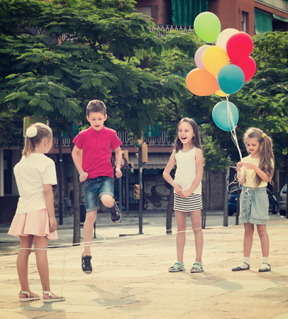 cheerful smiling children in elementary school age playing with chinese jumping rope at playgroundの写真素材