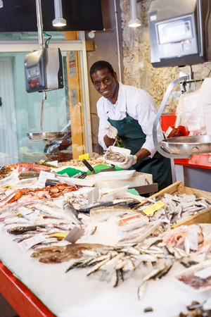 Positive male worker preparing fresh fish for saleの写真素材