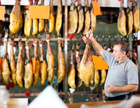 Portrait of handsome male client choosing Spanish jamon in shopの写真素材