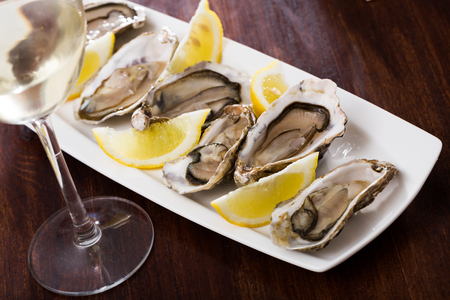 Tasty oysters with lemon on plate top viewの写真素材