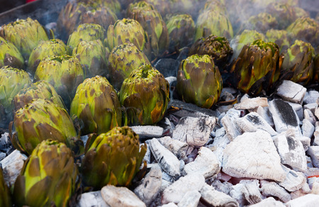 Closeup of artichokes being grilled on burning charcoal in brazierの写真素材