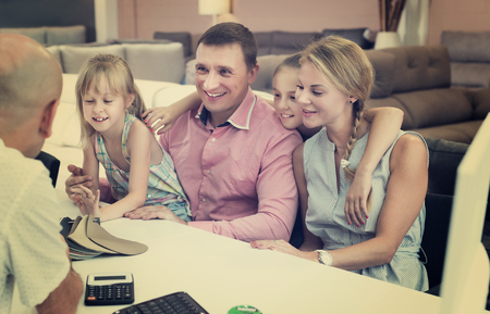 Family is consulting with the shop assistant about the color for new sofa.の写真素材