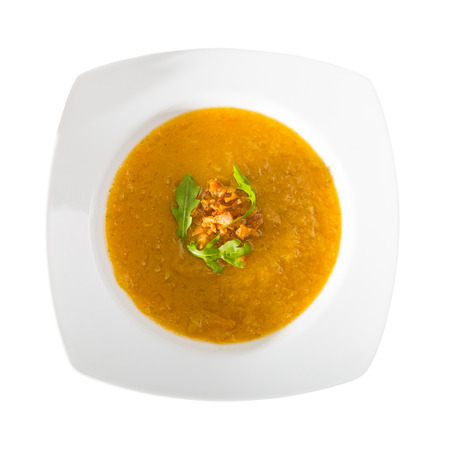 Top view of vegetable cream soup served in white plate with fresh greens. Vegetarian concept. Isolated over white backgroundの写真素材