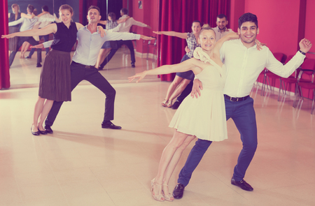 Young positive people dancing samba in pairs in dance hallの写真素材
