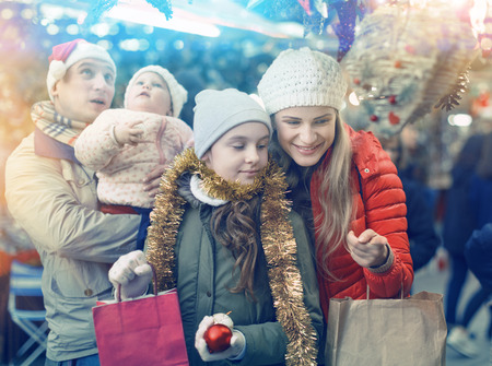 Portrait of cheerful man and woman with their happy daughters near counter buying Christmas decorationsの写真素材
