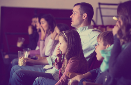 Spectators eating popcorn and fun to watch a movie at the cinemaの写真素材