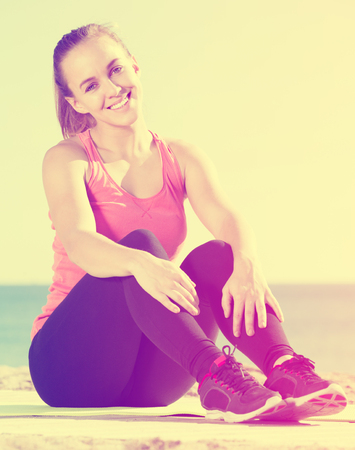 Beautiful young sporty woman exercising at sea beachの写真素材