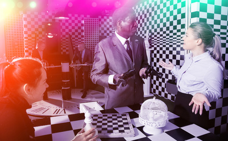 Group of colleagues solving puzzle together in quest room stylized like chessboardの写真素材