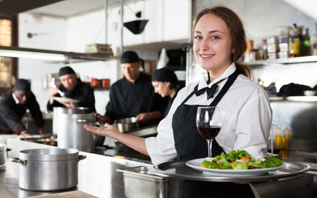 Waitress holding cooked meals at kitchen restaurant