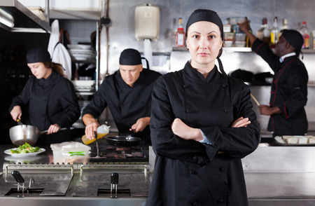 Positive female cook with cooked dish in restaurant kitchenの写真素材