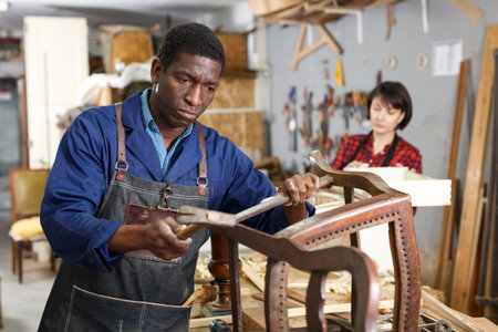 Portrait of craftsman restoring old chair in woodwork studio