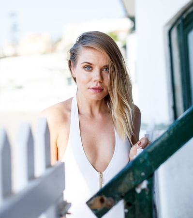 Closeup of young female in swimsuit posing near hotel fence at sea shoreの写真素材