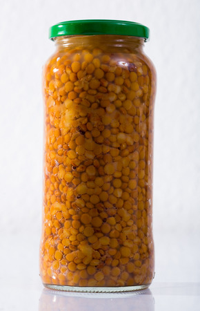 Glass jar with cooked lentils on white surface. Organic products for healthy eatingの写真素材