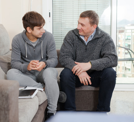 Guy with his father are resting and talking about teenage lifeの写真素材