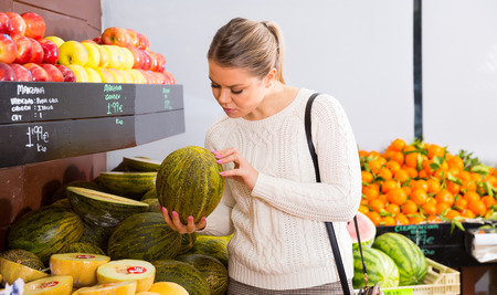 Portrait of smiling female customer choosing melon and fruits on the marketの写真素材