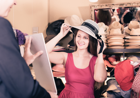 adult cheerful girl try on floppy hat from the range in storeの写真素材