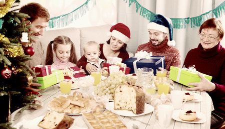 Family members presenting gifts during Christmas dinnerの写真素材