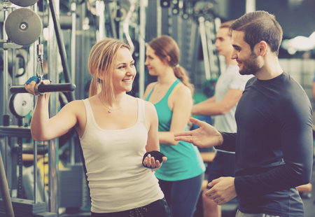 Positive smiling people having weightlifting training in health club